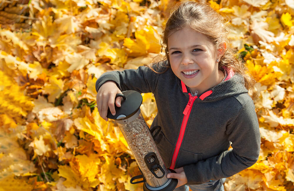 Child stands radiantly with her Apollo feeding system, which contains seeds